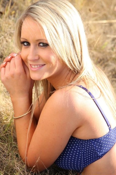 Blonde hottie Candice exposes her curves and natural tits in a meadow