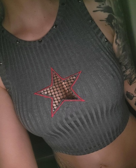 Cute tattooed amateur teases hotly with her covered big tits in her bedroom